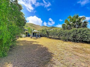 A backyard with a covered seating area, a small building, and a hill in the background. - Villa Sunrise Blue – Peaceful Retreat with Bay Views in Cul-de-Sac (Cul-de-Sac)