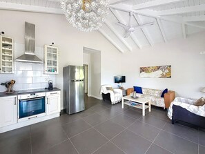 A modern kitchen with built-in appliances, a dining area with a sofa and table, and a living room with a television. - Villa Sunrise Blue – Peaceful Retreat with Bay Views in Cul-de-Sac (Cul-de-Sac)