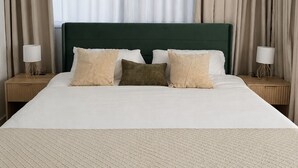 Ett hotellrum med en säng, en takfläkt, gardiner och sänglampor.