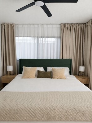 Ein Hotelzimmer mit einem Bett, einem Deckenventilator, Vorhängen und Nachttischlampen.