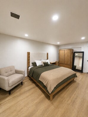 Ein Schlafzimmer mit einem Bett, einem Stuhl, einem Kleiderschrank und einem Spiegel.