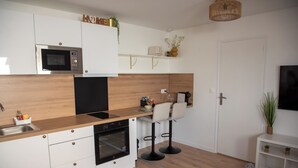 Cocina moderna con microondas, horno y taburetes de bar.