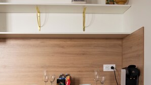 Un área de cocina con cafetera, copas de vino y un bol sobre una encimera de madera.