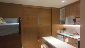 Ein gemütlicher Raum mit einem Bett, einer Küchenzeile und einem Holzschrank.