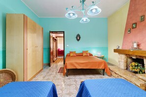 A room with a bed, a wooden wardrobe, a small table with a lamp, and a fireplace with flowers. - Apartment with Wi-Fi and Air Conditioning (Avola)