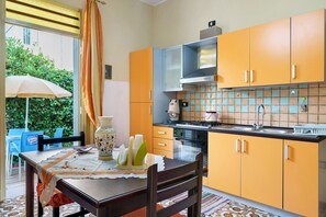 A kitchen with orange cabinets, a stove, and a tiled backsplash. - Apartment with Wi-Fi and Air Conditioning (Avola)