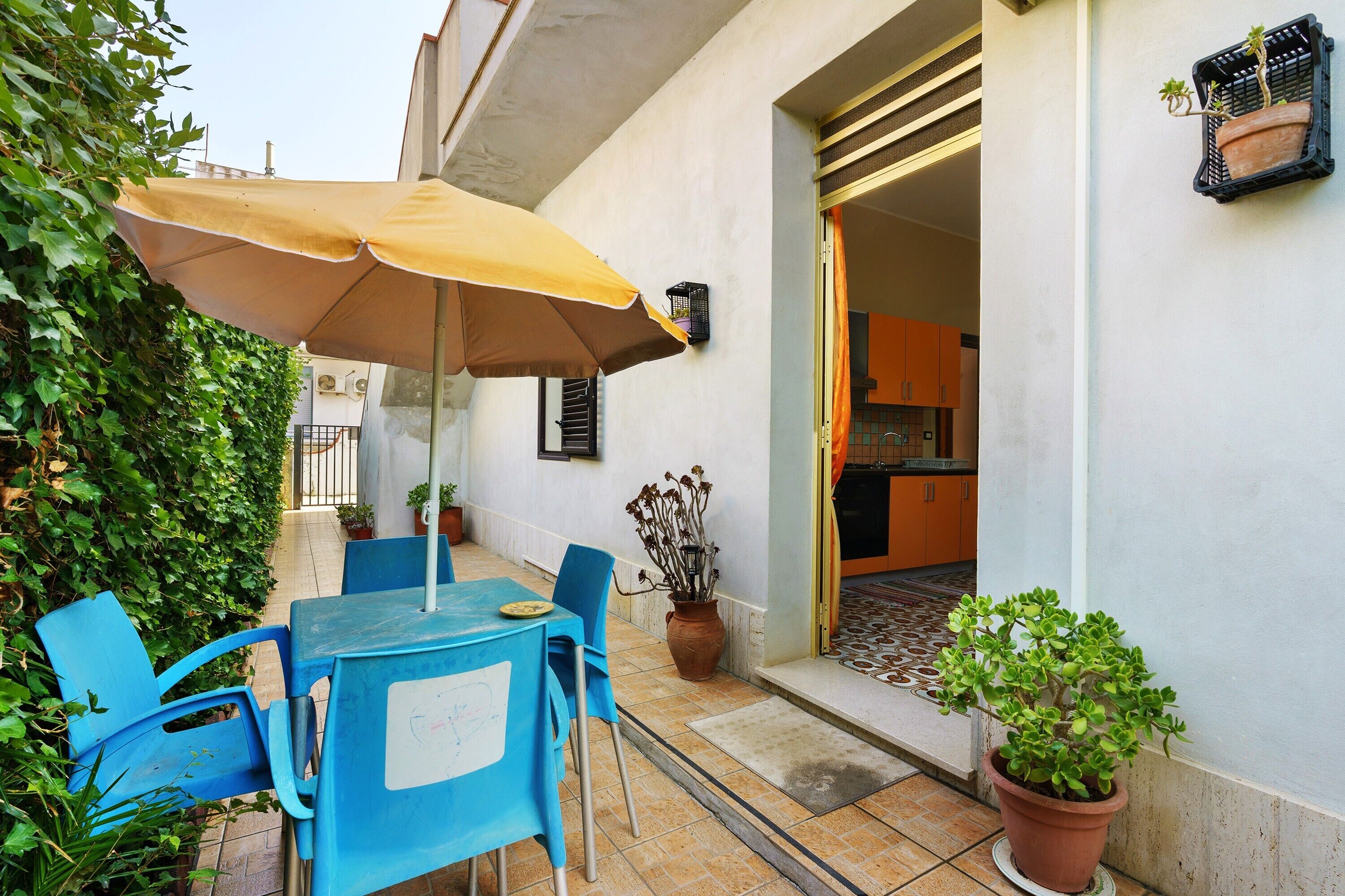Eine Terrasse im Freien mit Tisch und Stühlen, einem Blumentopf und einem gelben Sonnenschirm.