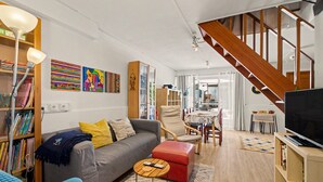 Ein modernes Wohnzimmer mit Sofa, Couchtisch, Fernseher und einer Treppe.