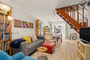 Ein modernes Wohnzimmer mit Sofa, Couchtisch, Fernseher und einer Treppe.