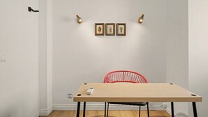 Ein Zimmer mit einem Holztisch, einem roten Stuhl und drei gerahmten Bildern an der Wand.
