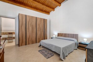 A bedroom with a bed, nightstands, a wooden wardrobe, a desk, and a patterned rug. - Attic with Sea View, Wi-Fi and Air Conditioning (Avola)