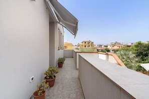 Ein schmaler Balkon mit Blumentöpfen und Blick auf die Nachbargebäude.