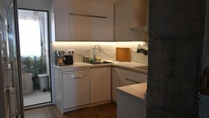 Moderni keittiö, jossa on valkoiset kaapit, sisäänrakennettu astianpesukone ja marmoritaso.