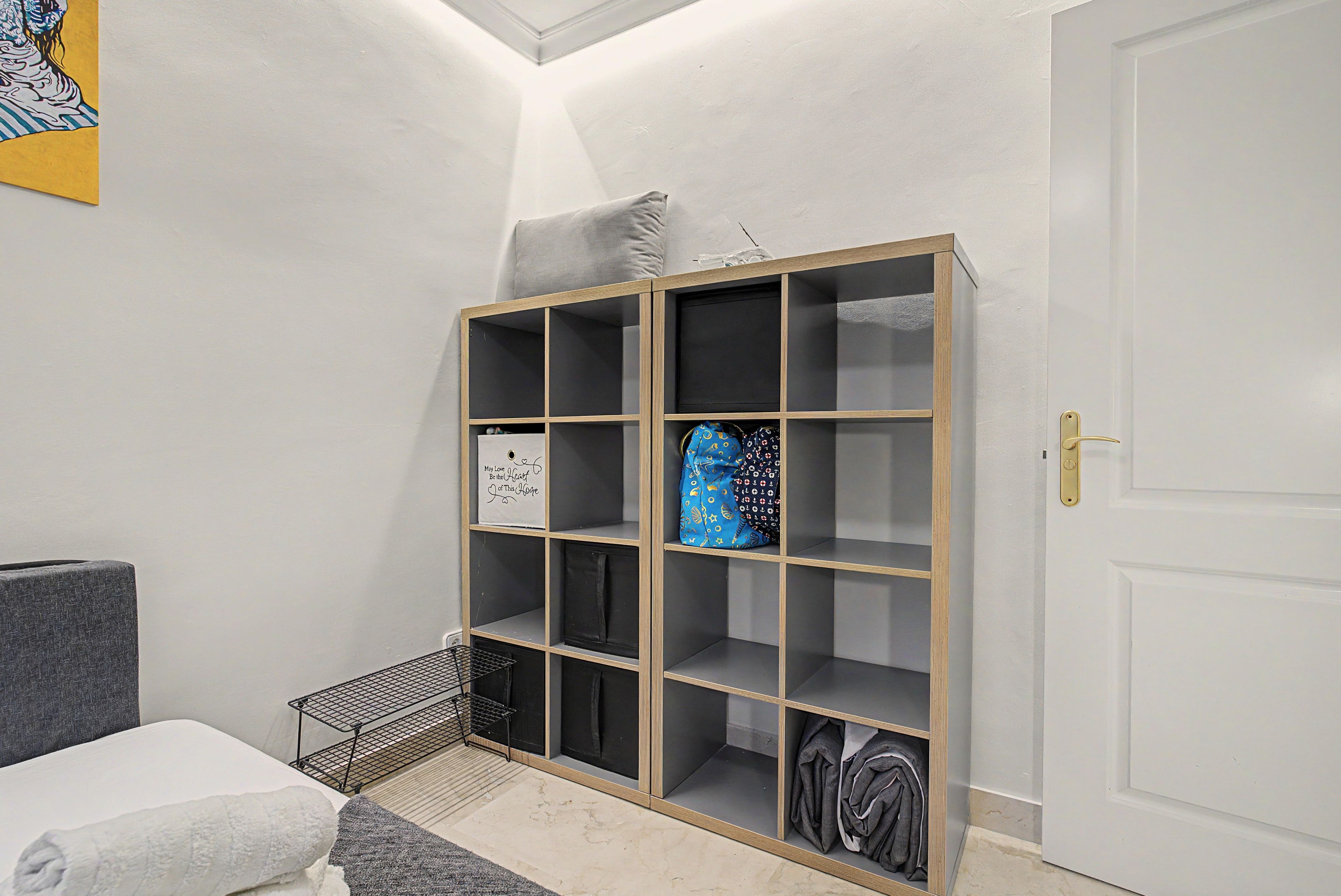 Quarto com armário embutido, cama e um pequeno espaço de estar.