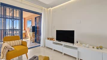 Una sala de estar moderna con sofá, reposapiés, televisor y mueble de entretenimiento.