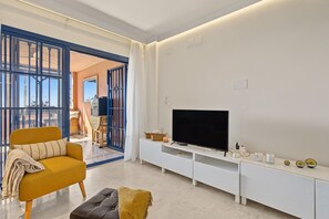 A modern living room with a sofa, ottoman, TV, and entertainment unit.