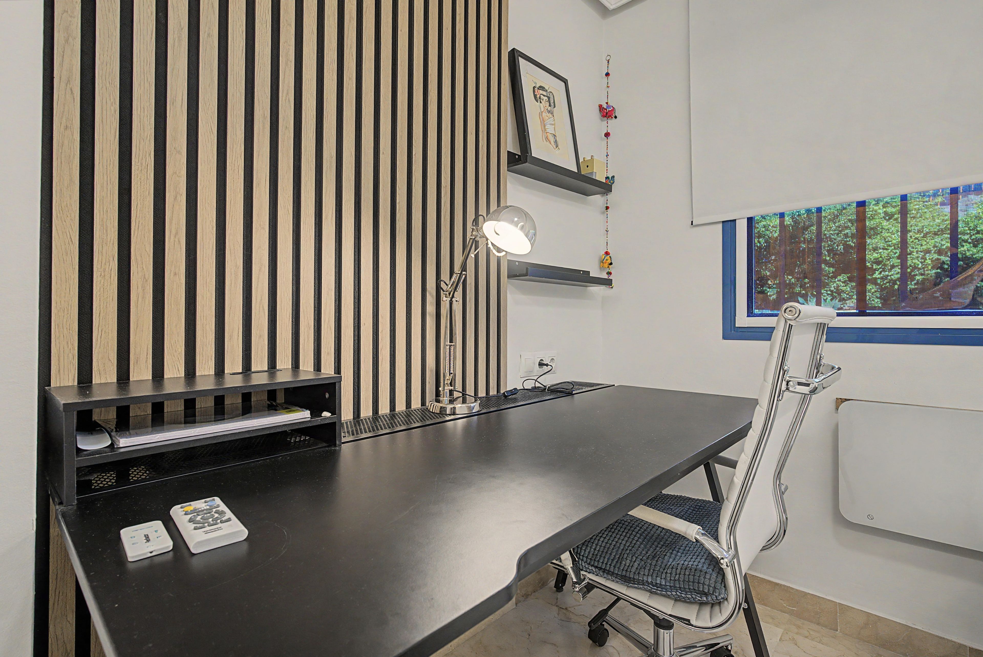 Een moderne kantoorruimte met een bureau, stoel en een groot raam.