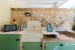 A bathroom with a sink, a microwave, a hammock, and a green cabinet. - Villetta Fico d`India by BarbarHouse (Sant'Isidoro)