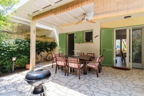 Um pátio externo com mesa, cadeiras, churrasqueira e uma bicicleta.