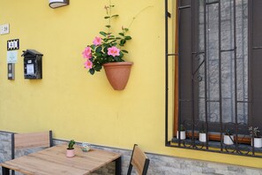 Eine gelbe Wand mit einem Fenster, einer Topfpflanze und einem Tisch mit Stühlen.