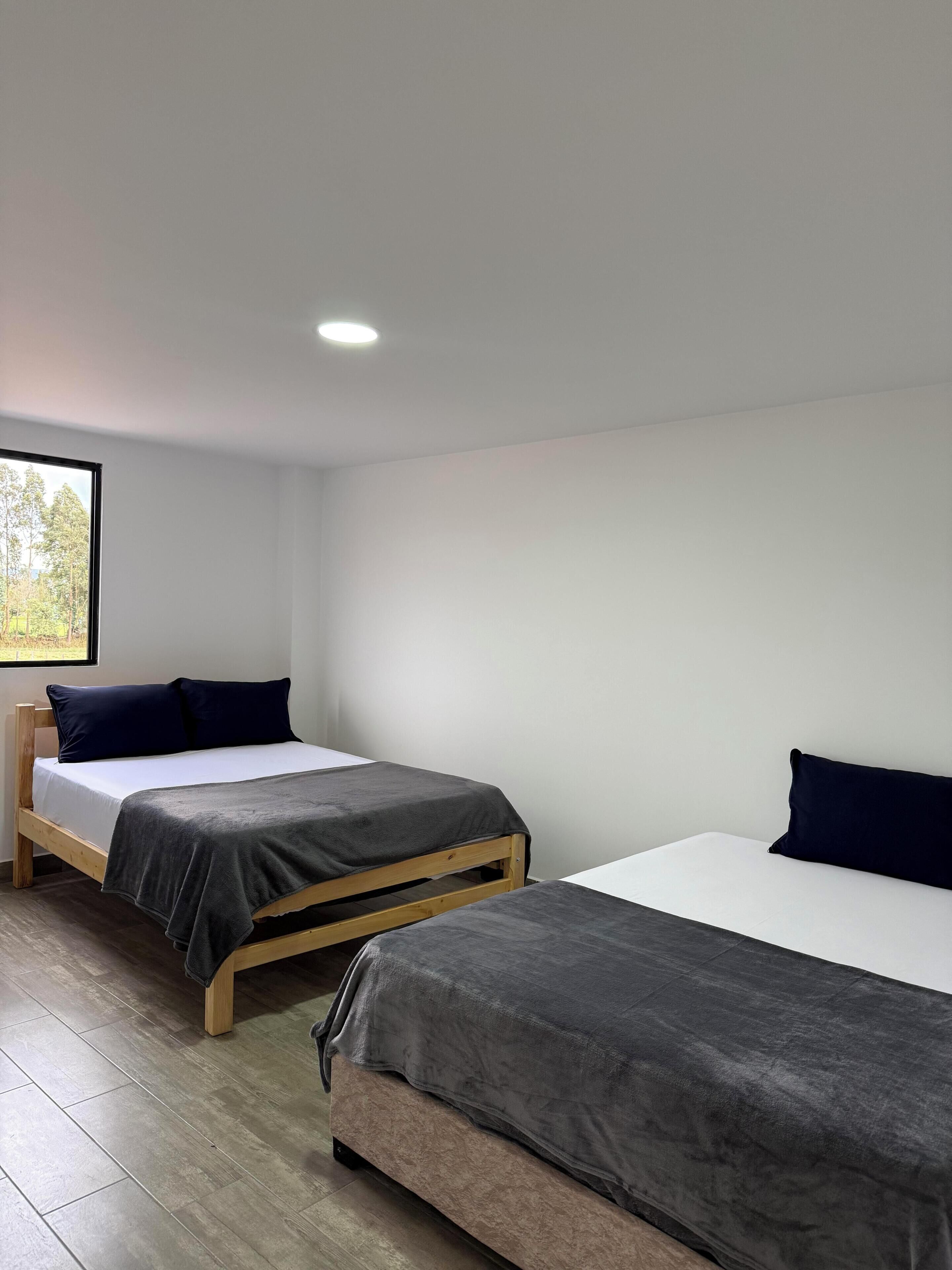 A room with two beds, a window, and a ceiling light.