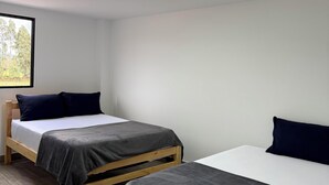Una habitación con dos camas, una ventana y una lámpara en el techo.