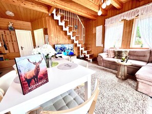 A wooden interior with a staircase, a sofa, a TV, and a table with a deer poster. - AUSZEIT Country House, surrounded by nature, with a grill and fire pit (Borod)