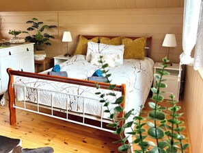 A bedroom with a wooden bed, white headboard, two bedside tables with lamps, a nightstand, and a potted plant. - AUSZEIT Country House, surrounded by nature, with a grill and fire pit (Borod)