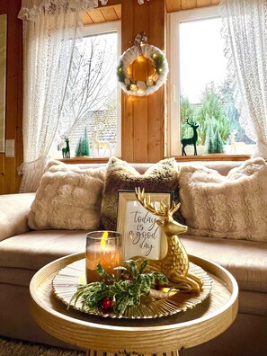 A cozy room with a sofa, a round wooden table with a candle, and decorative items including a moose and a wreath. - AUSZEIT Country House, surrounded by nature, with a grill and fire pit (Borod)