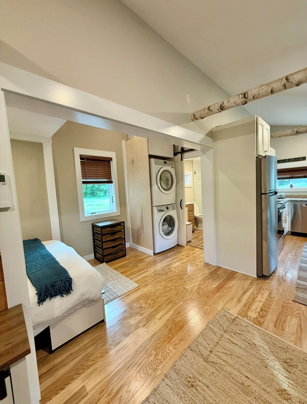 A compact living space with a bed, washing machine, and refrigerator.