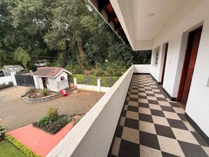 A balcony with a checkered floor, a small building with a red roof, and a lush green background. - ICG Premium 5-bedroom Villa Uzunguni, Arusha (Arusha)