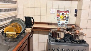 Una cucina con piano cottura, forno e mobili. C'è un espositore per piatti e un bollitore. Un poster è appeso al muro.