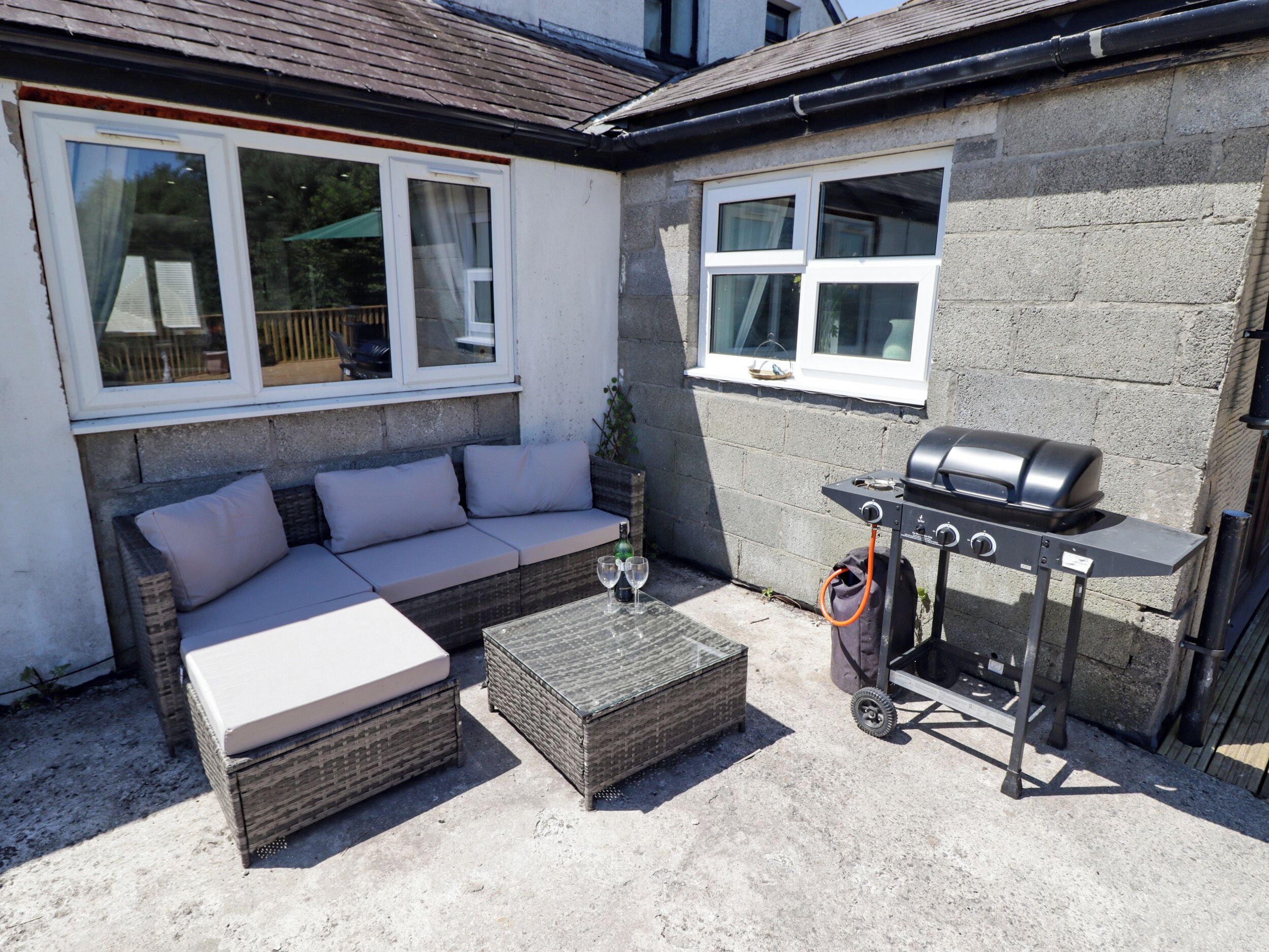 A patio with a sofa, a table, and a barbecue grill.