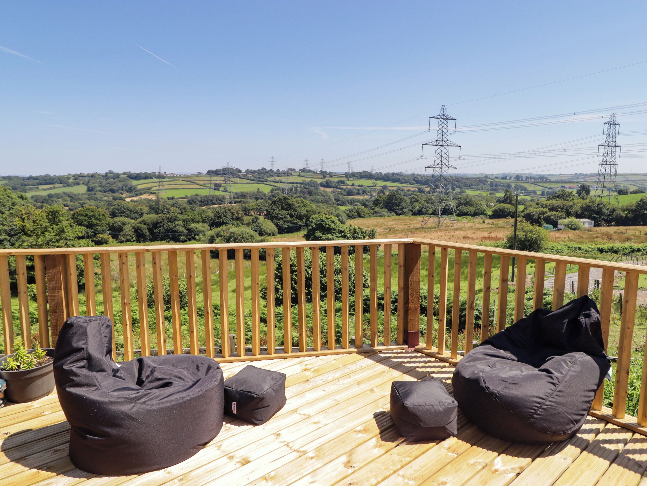 Eine Holzterrasse mit Sitzgelegenheiten und Blick auf die Landschaft.