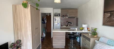 Een knus woongedeelte met een kitchenette, een eethoek en een slaapbank.