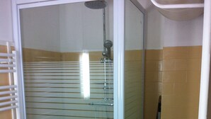A bathroom with a glass-enclosed shower, a toilet, and a radiator. - Bright studio apartment 50 meters from the beach (Mauguio)