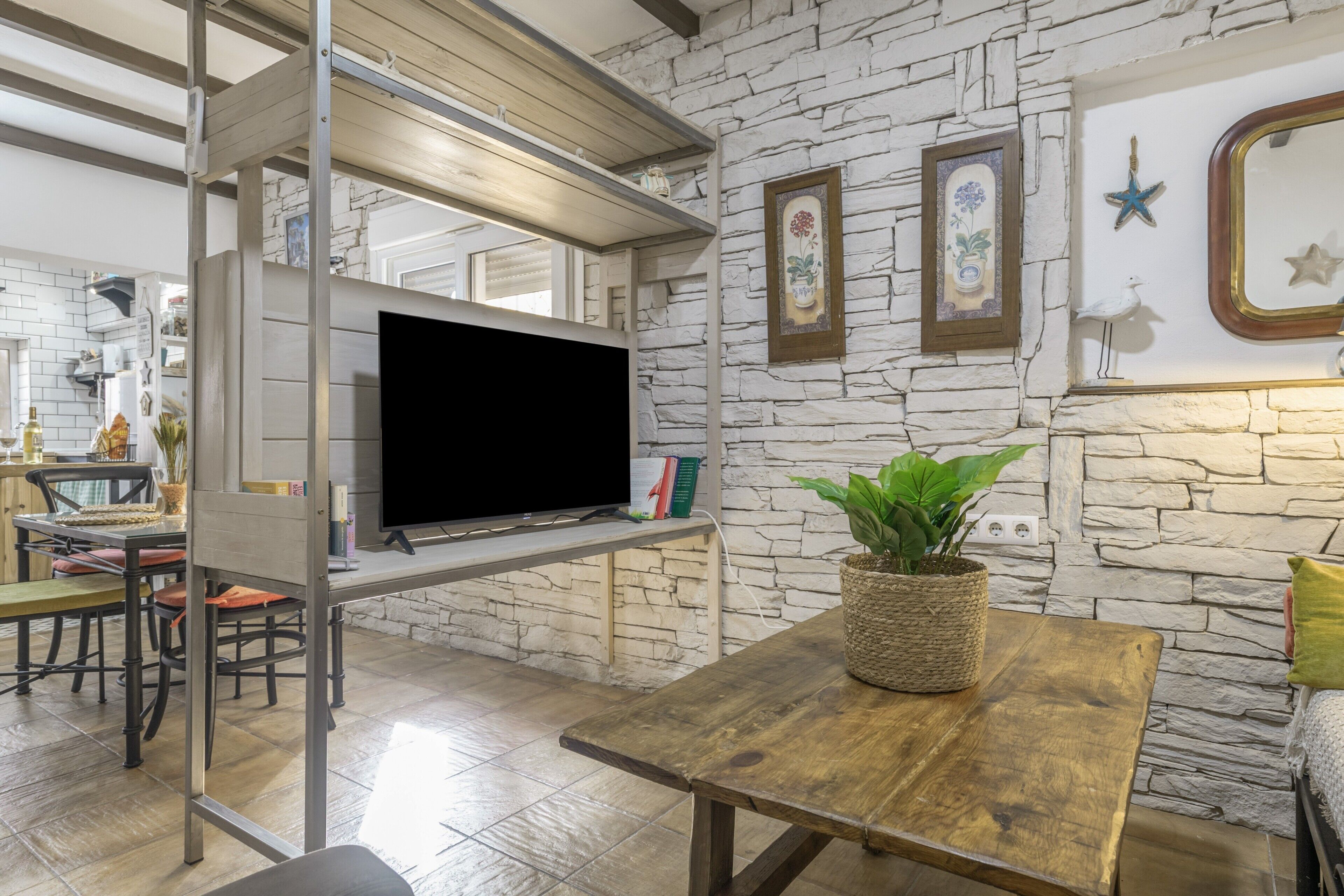 Een moderne woonkamer met een stenen muur, een flatscreen televisie, een houten tafel en een bankje.