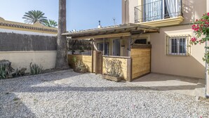 Un edificio con una zona exterior cubierta, una terraza de madera y un balcón con barandillas de metal.