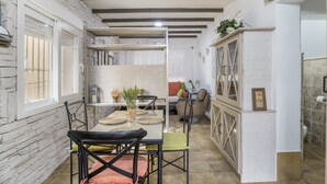 Una habitación con una mesa de comedor, sillas, un sofá, un armario y una ventana con barrotes.