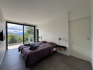 Een slaapkamer met een bed, een televisie, een nachtkastje en een schuifdeur naar een balkon.