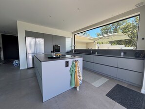 A modern kitchen with a central island, built-in appliances, and a large window offering a view of the outdoors. - Exclusive modern vacation home with spectacular views and beautiful terraces (Maureillas)