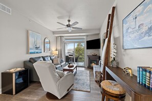 Een woonkamer met een bank, fauteuil, salontafel, open haard en een televisie.