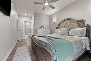 A bedroom with a large bed, a ceiling fan, a nightstand, and a dresser. - New Egg Harbor Condo • Steps to Shipwrecked, Marina & Beach • 2 King Suites (Egg Harbor)
