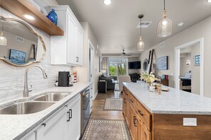 A modern kitchen with a large island, stainless steel appliances, and pendant lighting. - New Egg Harbor Condo • Steps to Shipwrecked, Marina & Beach • 2 King Suites (Egg Harbor)