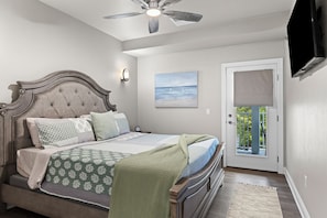 Une chambre à coucher avec un lit, un ventilateur de plafond, un tableau et une porte donnant sur l’extérieur.