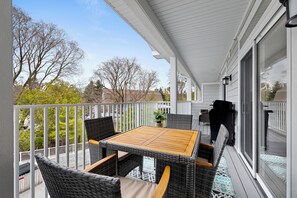 A balcony with wicker furniture, a table, and a grill. - New Egg Harbor Condo • Steps to Shipwrecked, Marina & Beach • 2 King Suites (Egg Harbor)
