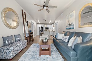 A modern living room with a sofa, a coffee table, and a ceiling fan. - New Egg Harbor Condo • Steps to Shipwrecked, Marina & Beach • 2 King Suites (Egg Harbor)