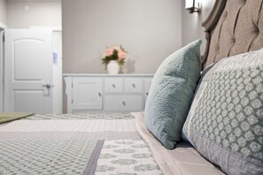 A bedroom with a bed, pillows, a dresser, and a vase with flowers. - New Egg Harbor Condo • Steps to Shipwrecked, Marina & Beach • 2 King Suites (Egg Harbor)