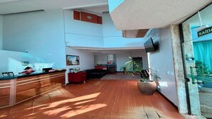 A spacious lobby with a reception desk, seating area, and a large potted plant. - MAISON COLLECTION PREMIUM (Porto Velho)