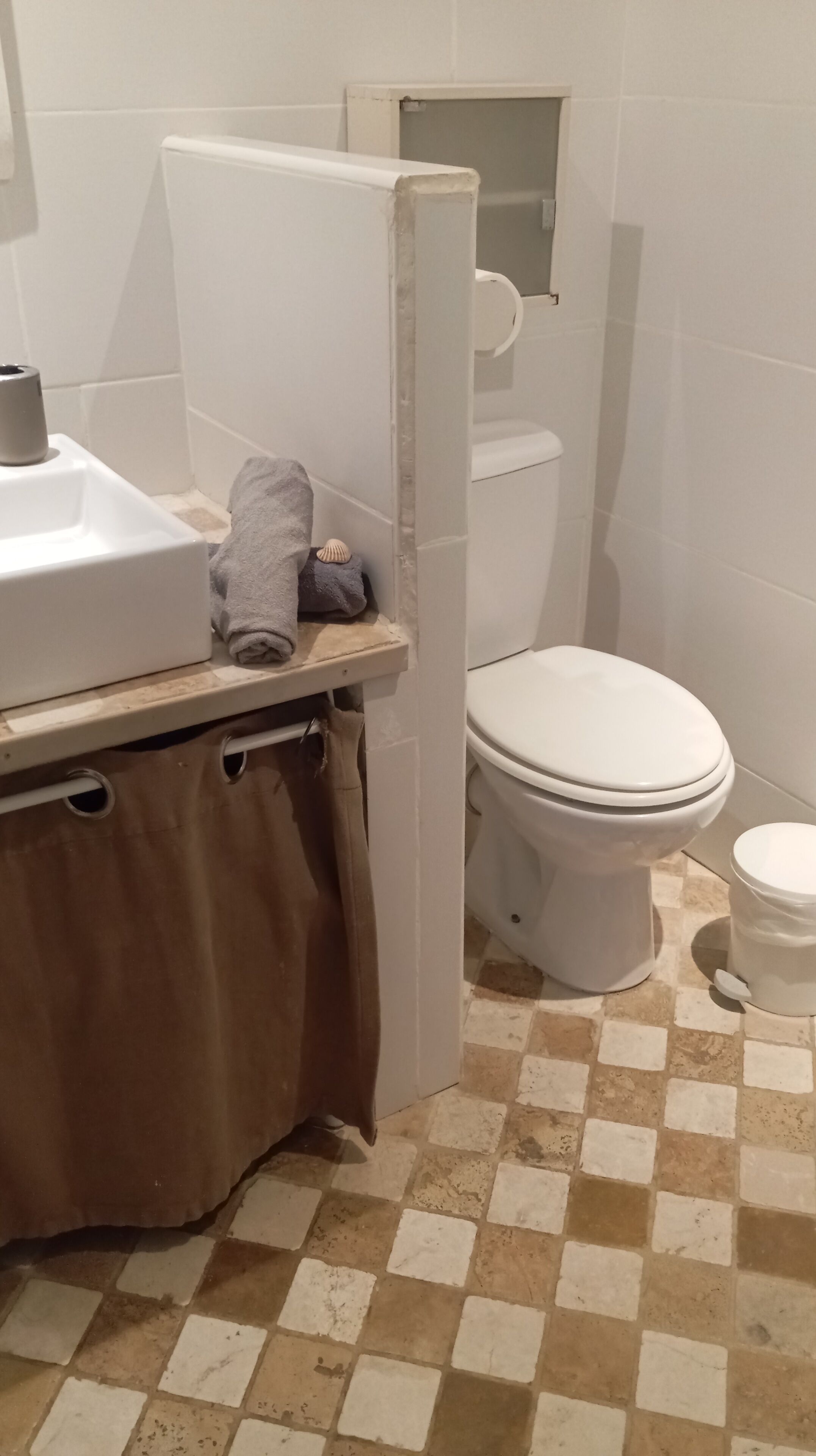 Une salle de bain avec un lavabo blanc, des toilettes et un espace douche.